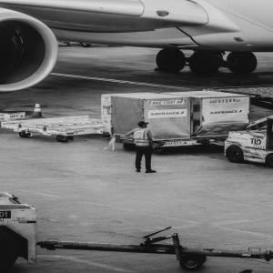 about-01 Black and white image of airport crew managing cargo near airplane